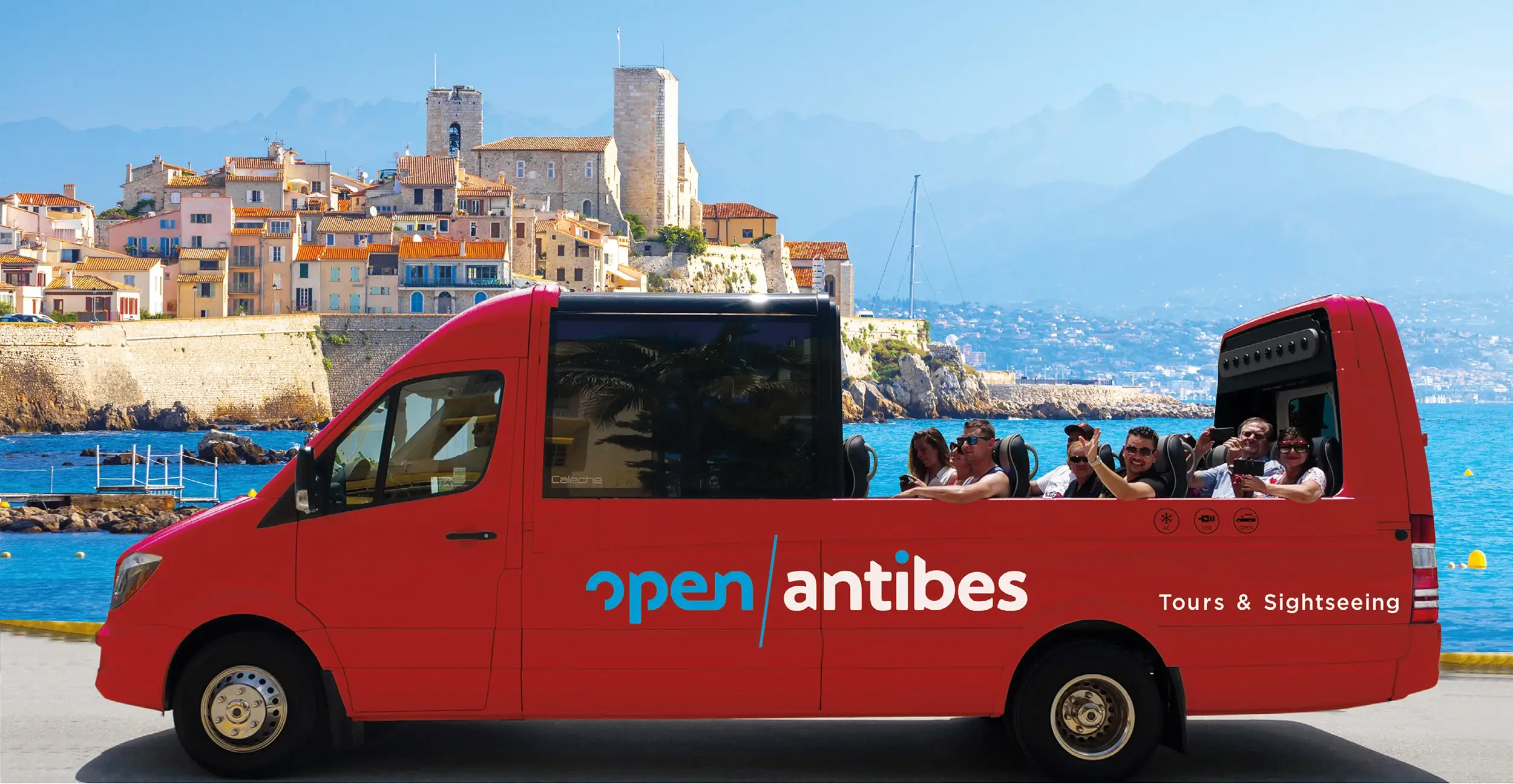 Le bus rouge cabriolet Open Antibes et ses passagers devant le vieil Antibes